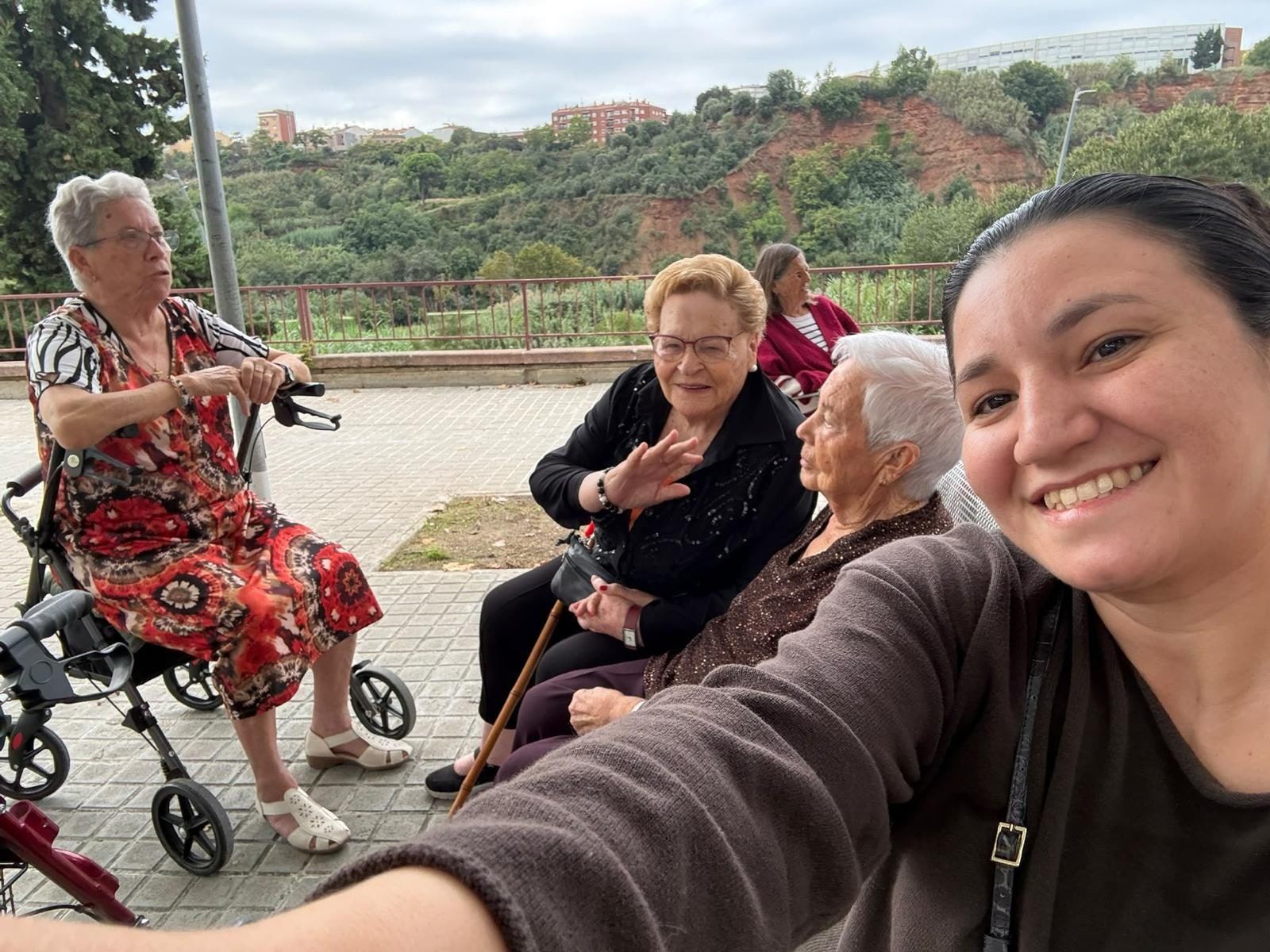 Cuidadora d'Atention de passeig amb un grup de senyores grans assegudes en un banc a l'aire lliure